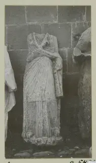 Headless draped stone statue of a standing figure, Arsos, photographed against a block wall