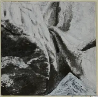 Close view of a marble sculpture surface with deep folds and dark hollows against pale raised areas