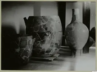 Stone Age pottery: three large mended vessels on wooden stands and plinths in a display room