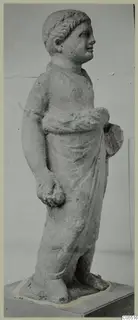 Standing limestone statue of a young figure in a draped garment, from Mersinaki, photographed on a plinth