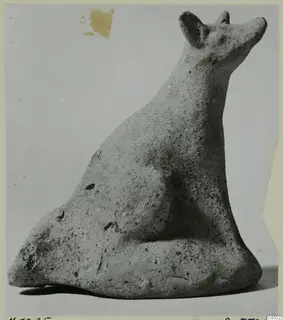 Terracotta figurine of a seated animal with upright pointed ears and a raised snout