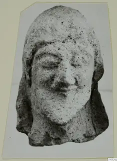 Terracotta head of a figure from Mersinaki, shown frontally with downcast eyes and hair falling to the shoulders