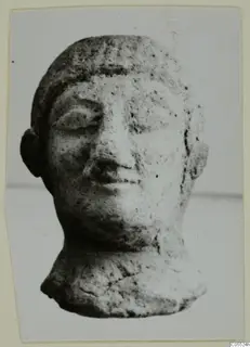 Small terracotta head of a figure from Mersinaki, shown face forward against a plain background
