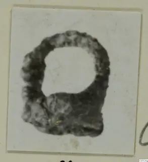 Corroded iron object from Marion, a dark ring-shaped form with a rounded top and flat lower edge, on a card mount.