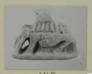 Small grey object from Amathus with a pierced hole and vertical ridges, shown on a card mount