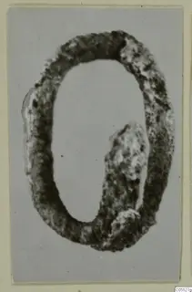 Silver ring, oval in shape and heavily corroded, shown against a plain grey background.