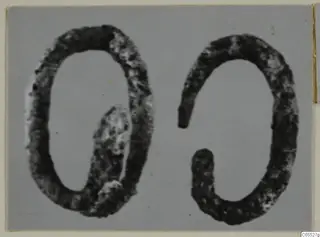 Two dark, corroded silver rings lying side by side on a grey backdrop