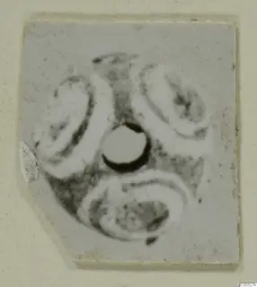 Small flat object from Marion, Tomb 26, with a central round hole and three curved motifs around it