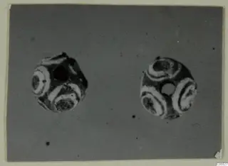 Two beads from Marion, Tomb 26, with white banded ring patterns on dark surfaces.