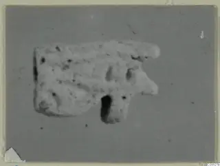 Small pale object on a grey backdrop, from Amathus tombs 1–9 finds, with a rounded projection and a dark hole below