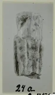 Fragmentary sculpture, possibly a figure, pale and rough-surfaced, shown on a grey card mount