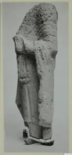 Limestone sculpture fragment of a standing figure from Mersinaki, photographed against a grey backdrop