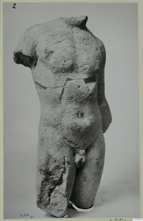 Limestone male torso from Mersinaki, headless and armless, photographed against a plain grey backdrop.
