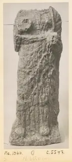 Eroded limestone sculpture of a standing figure from Mersinaki, photographed upright on a grey backdrop
