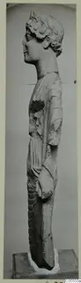 Standing limestone statue from Mersinaki, seen in side profile, with a damaged upper torso.