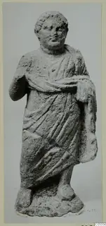 Standing draped statue from Mersinaki, with one arm bent at the chest, photographed against a grey backdrop