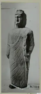 Limestone statue from Mersinaki of a standing figure in a draped garment, head and body shown