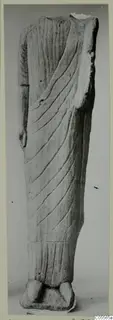 Headless limestone statue of a standing figure in a long draped garment with diagonal folds, on a plinth.