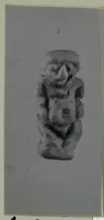Small figurine of a squat figure with a large nose and a flat cap, arms folded across the chest.