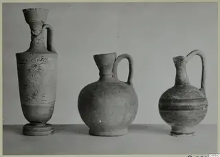 Three pottery vessels standing in a row on a plain surface, from Marion.