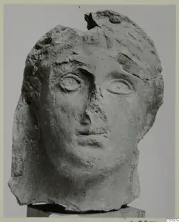 Carved head from Mersinaki, front view on a block, with the top and back of the head broken away.