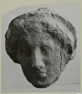 Head of a small figure in terracotta or limestone, with a worn face and pitted surface, from Mersinaki
