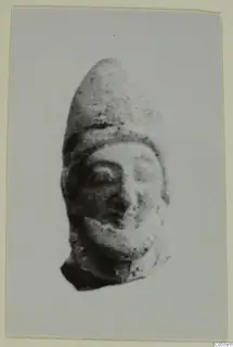 Terracotta head fragment with a tall pointed cap and a broken base, from Mersinaki