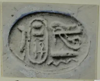 Scarab seal with an oval frame and incised signs, including an eye-like motif, shown in close-up.
