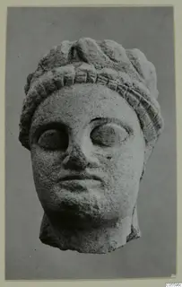 Limestone head from Mersinaki, photographed face-on against a plain grey background
