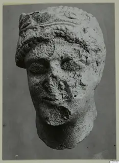 Limestone head sculpture from Mersinaki, shown frontally, with a broken nose and damaged lower face and chin.