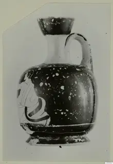 Jug with a flared mouth, one handle and a partly visible painted figure on its body