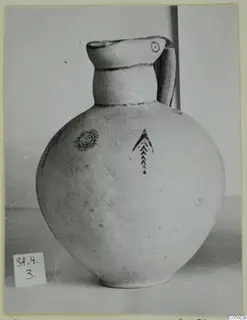 Pottery White Painted IV jug with a spiral motif and a chevron motif in dark paint on its round body