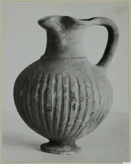 Jug with a trefoil mouth, one handle and vertical fluting on the body, standing on a small foot.