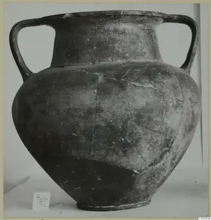 Two-handled pottery jar with a dark, worn surface, photographed on a plain background
