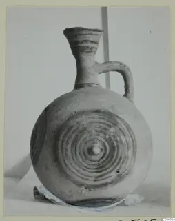 Pottery White Painted I jug with a flaring neck, a strap handle and concentric circles on its body