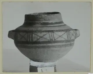 Bichrome IV pottery vessel from Amathus with two side handles and painted bands with cross-hatched panels, photographed on a stand