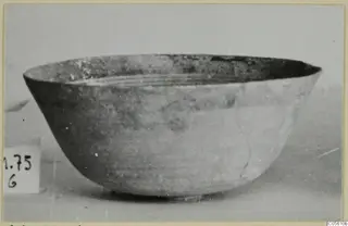 Pottery bowl with a flaring wall and smooth surface, photographed in side view beside a number label.