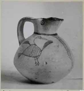 White Painted IV juglet with a bird and a branch-like pattern painted in dark paint on a pale body.