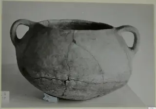 Coarse pottery cooking-pot with two loop handles, photographed on a light surface.