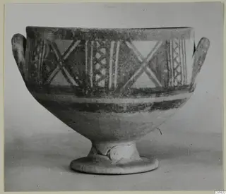Pottery Bichrome II footed bowl with two side handles, painted with crossed diagonal strokes and vertical bands.