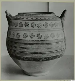 Two-handled painted pottery jar with concentric circle motifs and horizontal bands in dark paint on a pale surface.