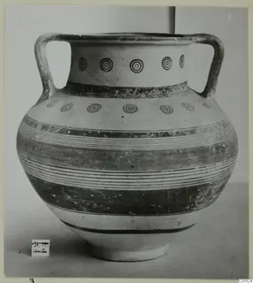 Two-handled pottery jar with concentric circles and horizontal bands, photographed against a plain background.