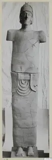 Terracotta statue of a standing figure with a cap-like head and no arms, on a square base.