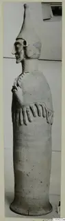 Terracotta Proto-Cypriote I, a tall standing figure in profile with a tapering cap and arms bent across the chest