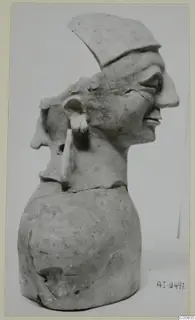 Clay bust with two profile faces, one wearing a flat cap-like top, on a rounded base