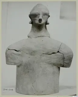 Terracotta figure with folded arms and a rounded head, photographed from the front at Ayia Irini