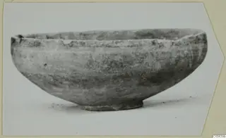 Pottery bowl with a rounded body and low ring foot, seen from the side against a pale background.