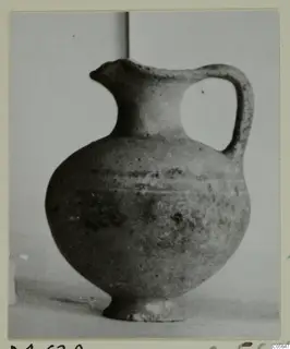 Pottery jug with a trefoil-style spout, a single loop handle and a rounded body, photographed against a plain backdrop.