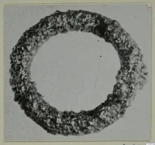 Silver ring-shaped object with a rough, corroded surface