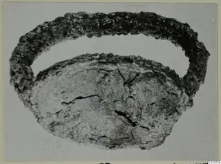 Corroded metal ring with a flattened oval piece below it, from Marion.